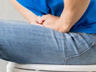 man sitting on a toilet holding lower abdomen, indicating constipation discomfort and digestive issues