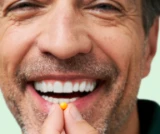 Gros plan d'un homme souriant qui est sur le point de prend un comprimé DulcoLax