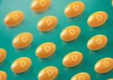 Orange capsules with the letter "D" scattered on a teal surface.