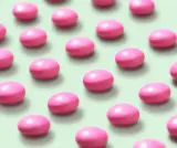 Rows of pink oval pills on a light green background.