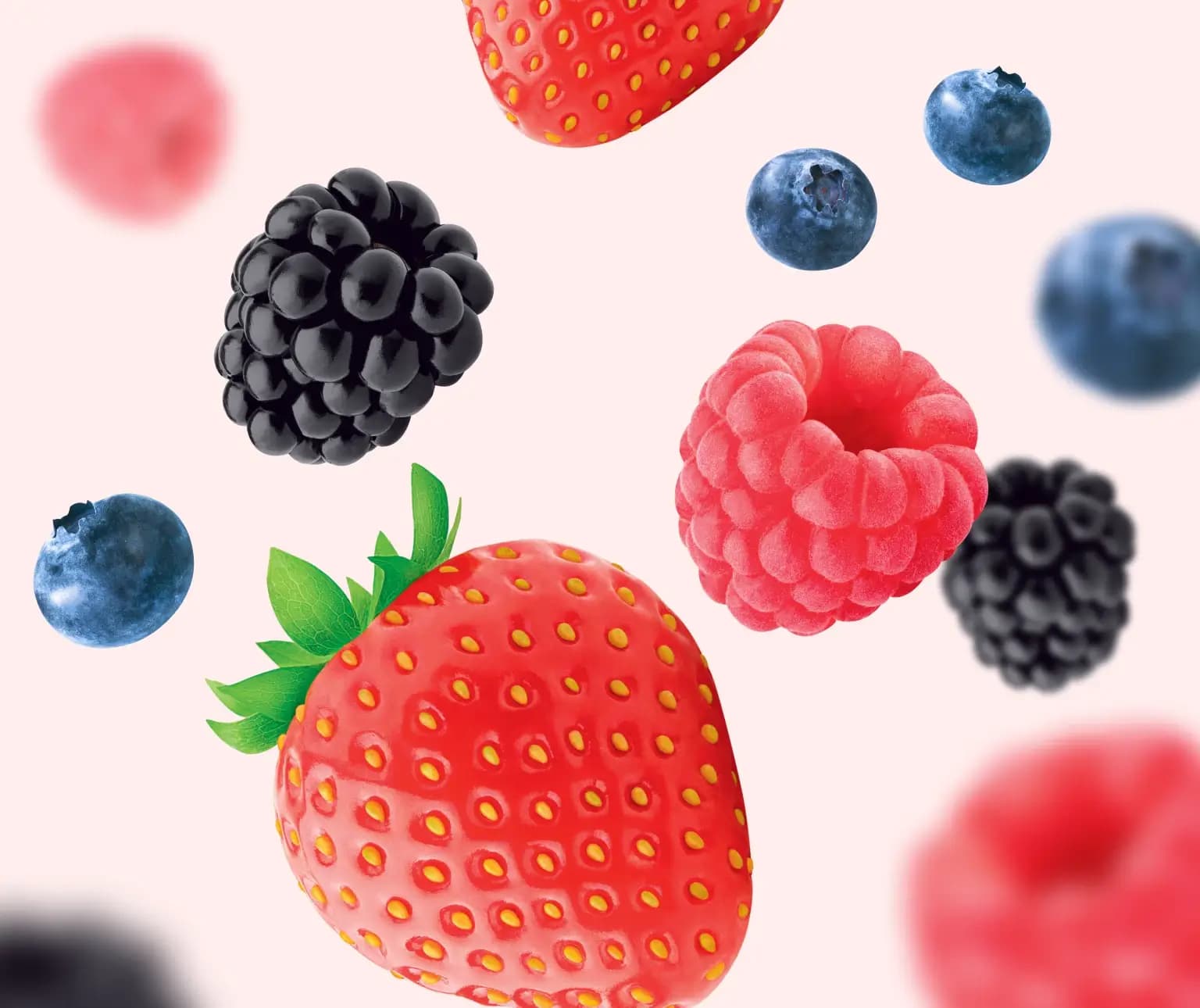 Strawberries, raspberries, blackberries, and blueberries on a light pink background.