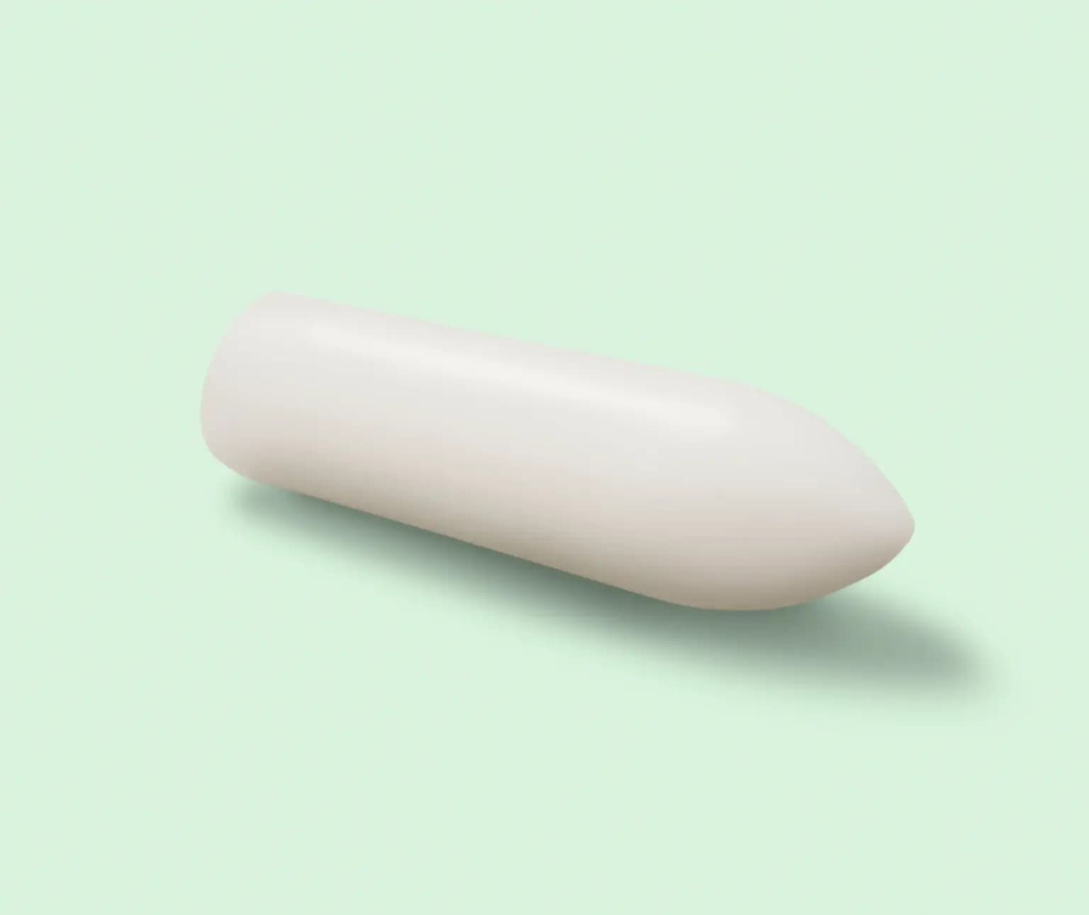 White cylindrical suppository on a light green background.