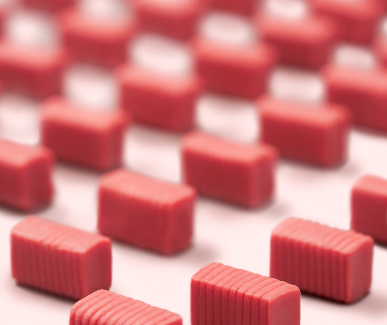 Rows of small, pink rectangular erasers on a light surface.