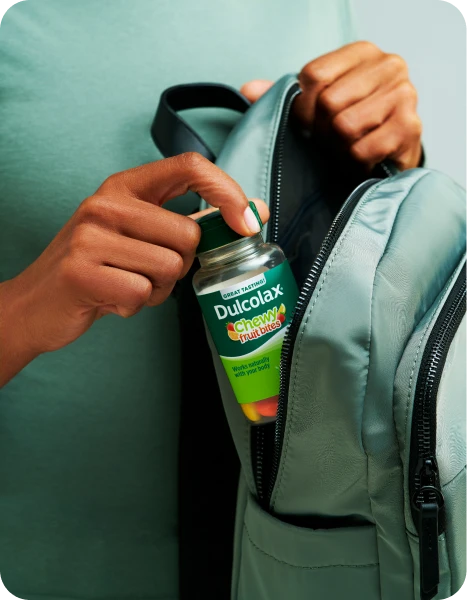 Person placing Dulcolax Chewy Fruit Bites in a backpack.