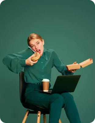 Person multitasking by talking on phone, eating a bagel, and using a laptop, with coffee on lap.