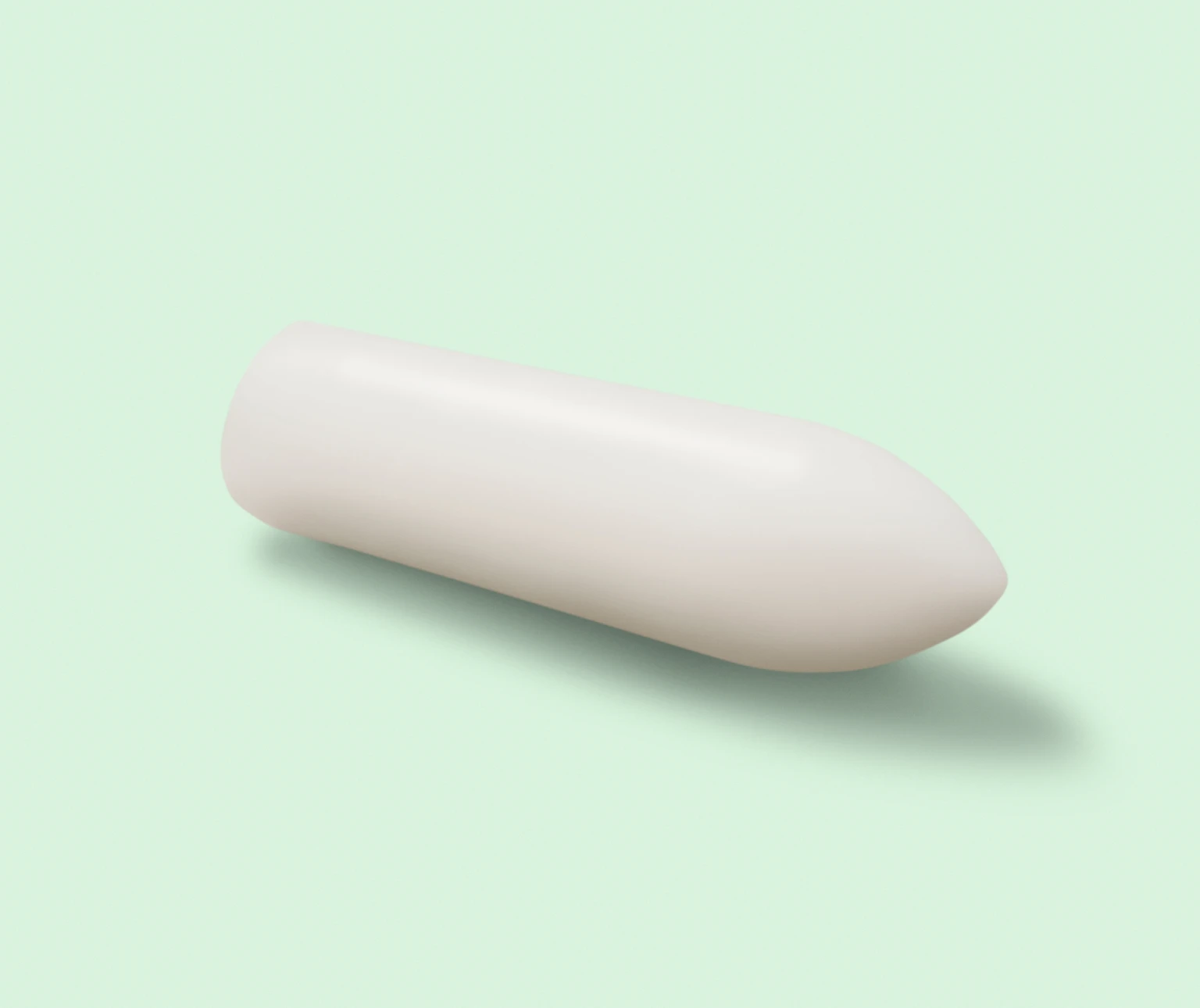 White cylindrical suppository on a light green background.
