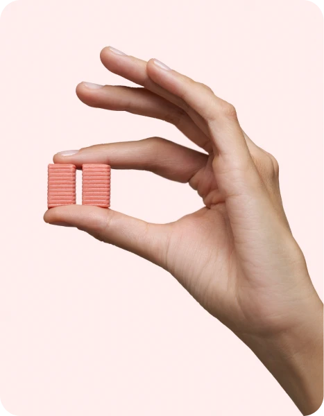 A hand holding two pink wafer biscuits between fingers.