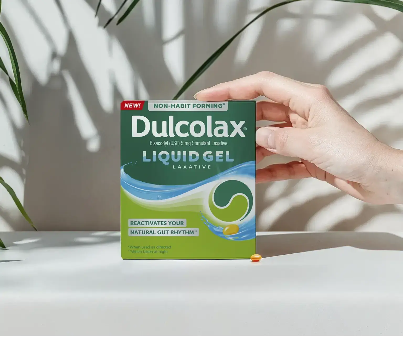 Dulcolax Liquid Gel Laxative, Bisacodyl 5mg, held in hand with sunlight and plant shadows.