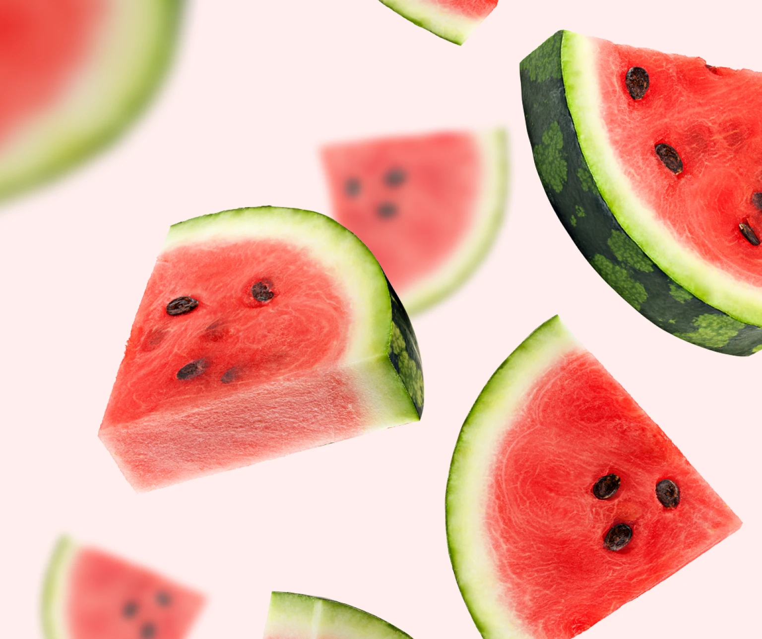 Slices of juicy watermelon with seeds on a light pink background.