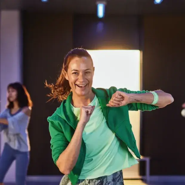 Smiling woman with curly hair wearing a green sweater and earrings.