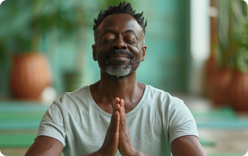 Man meditating with hands in prayer position indoors.