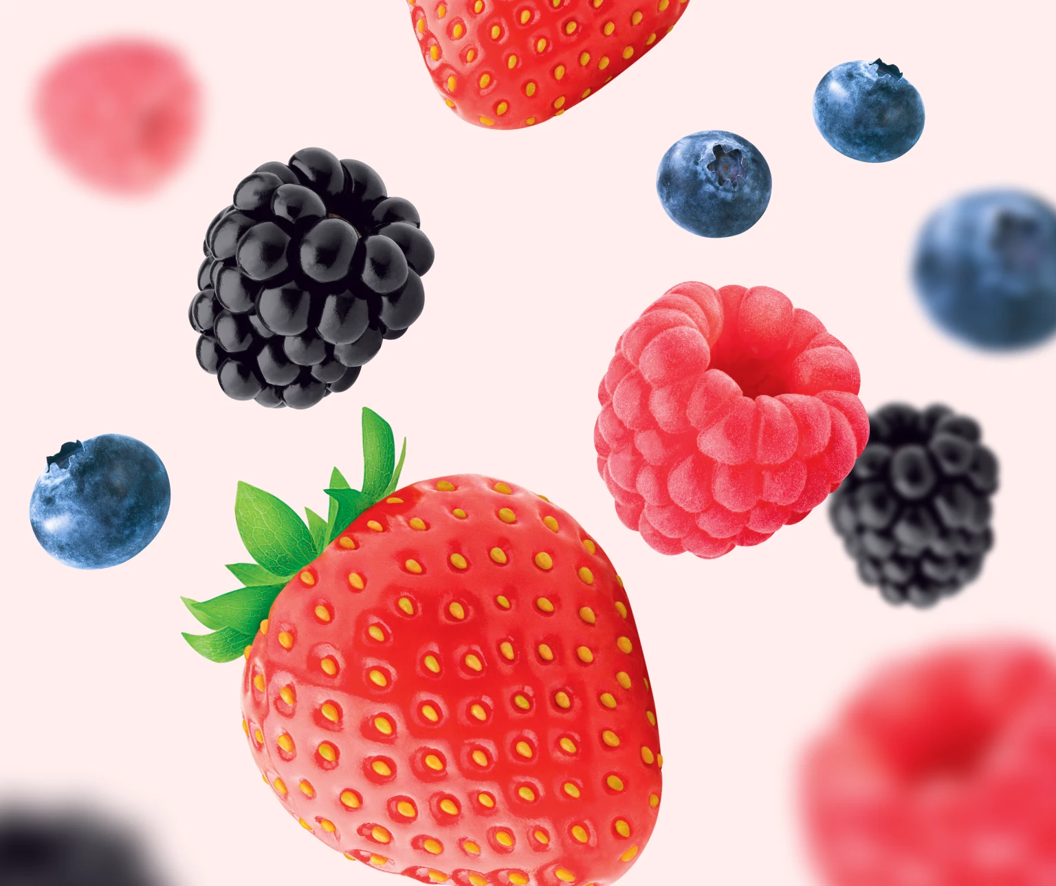 Photo d’une douzaine de petits fruits mélangés (fraises, bleuets, framboises et mûres) flottant sur un fond rose pâle pour mettre en valeur le goût délicieux et les arômes naturels des Soft Chews Kids
