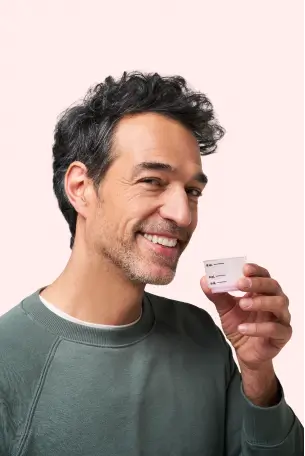 Man smiling while holding a small measuring cup.