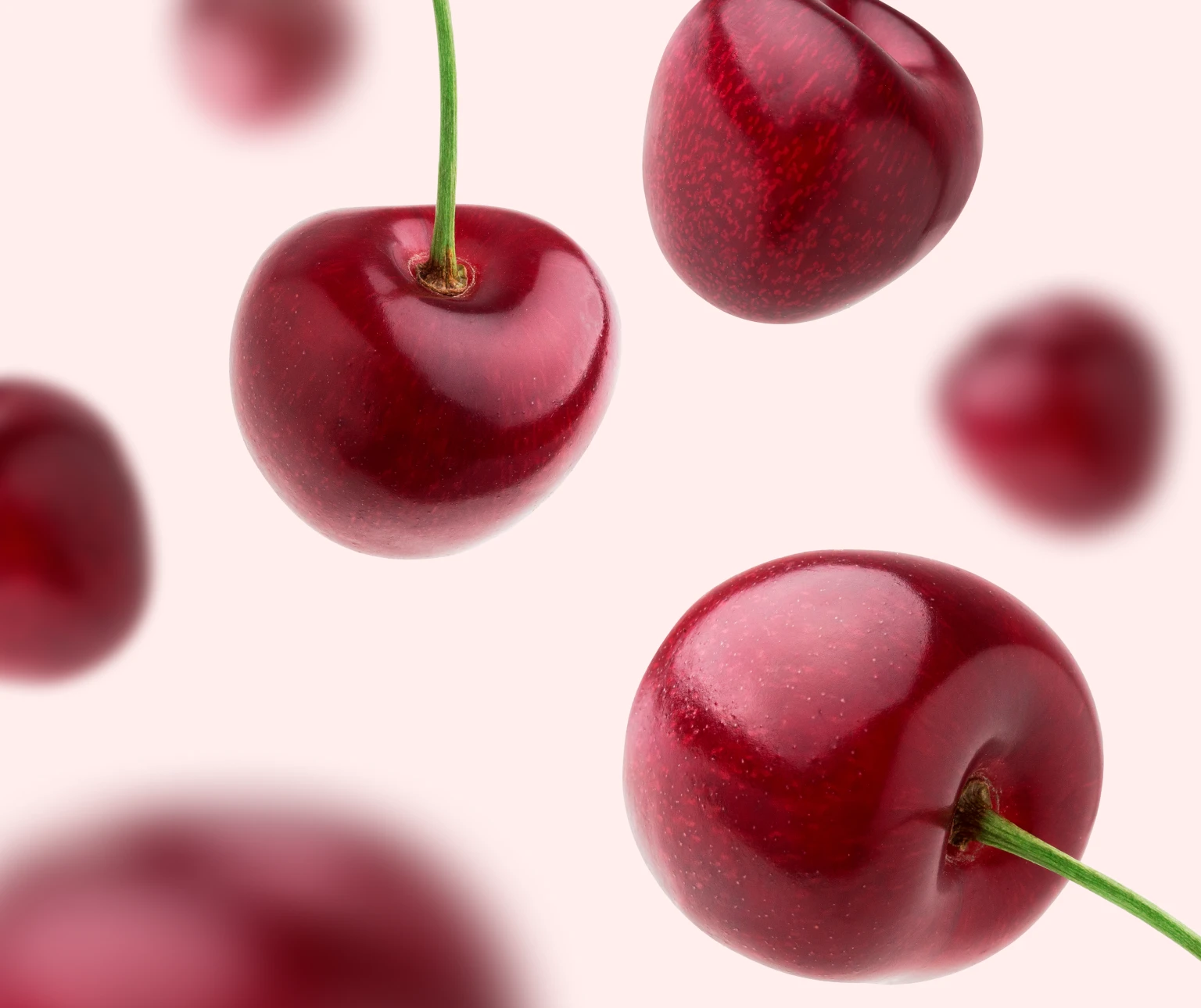 Photograph of cherries floating around in front of a light pink background to highlight the cherry flavour of DulcoLax Liquid.