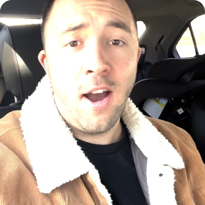 Person in a car wearing a brown jacket with a white fleece collar.